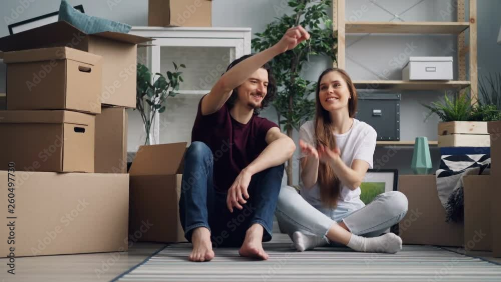 Bearded guy is giving keys to pretty girlfriend then kissing her sitting on floor in new apartment talking and smiling. Happiness, relationship and relocation concept. Bearded guy is giving keys to pretty girlfriend then kissing her sitting on floor in new apartment talking and smiling. Happiness, relationship and relocation concept.