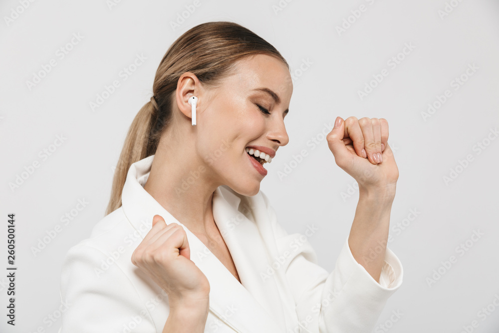 Beautiful amazing woman posing isolated over white wall background listening music with earphones. Beautiful amazing woman posing isolated over white wall background listening music with earphones.