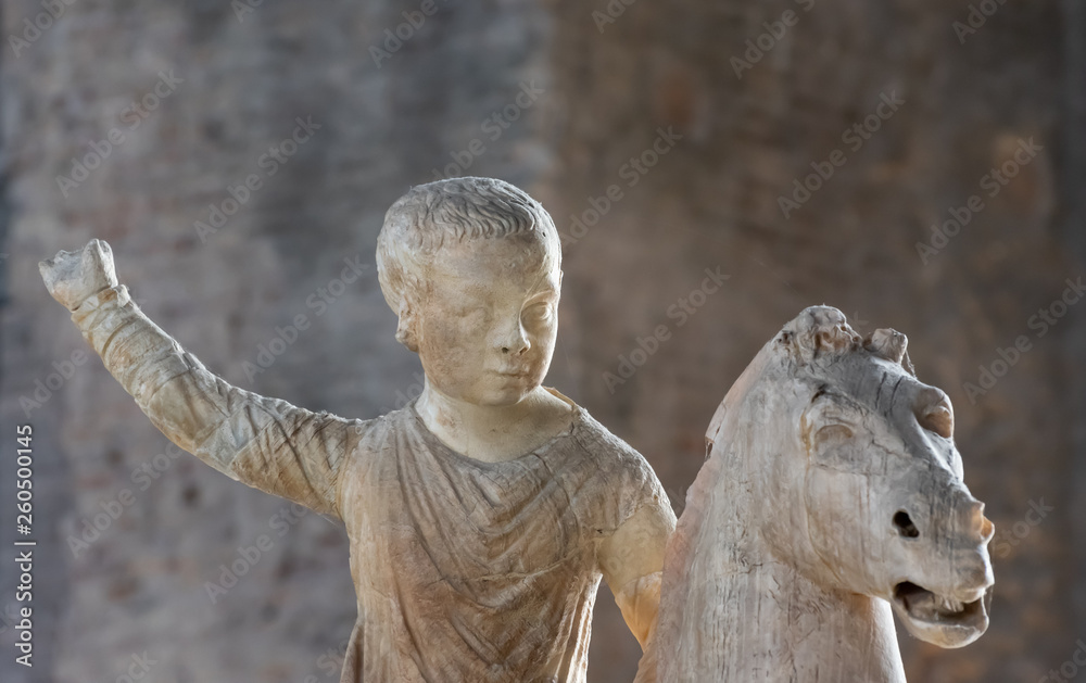 Ancient roman statue sculpted on marble showing a boy riding a horse