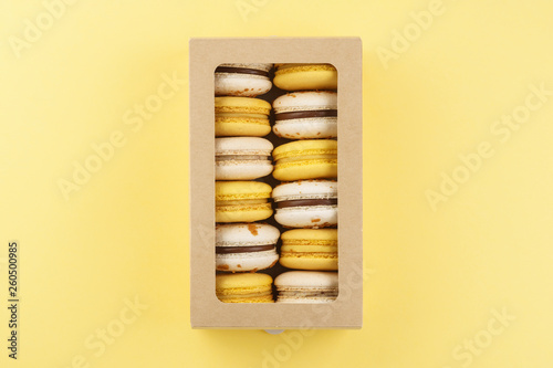 Colorful macarons in a box on yellow background. © Tatiana Atamaniuk