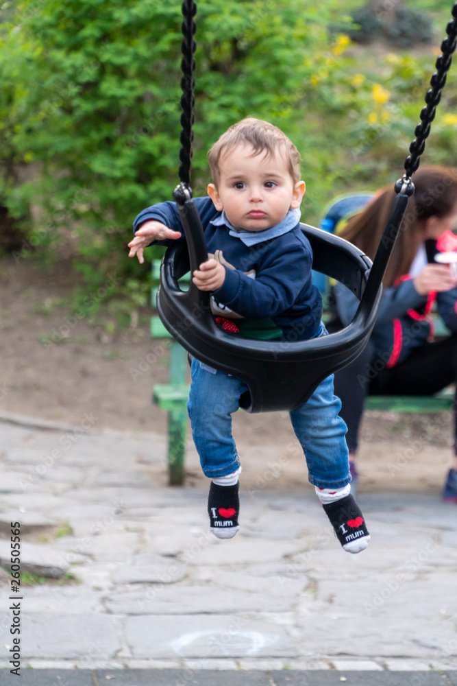 Smiling baby boy on a children swing Smiling baby boy on a children swing