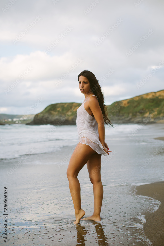 Young latin mediterranean woman at beach towards the sea. Vacation relax and summer freedom concept.