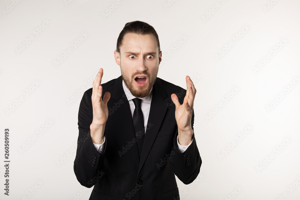 Attractive handsome bearded man in black suit and tie over white background surprised and shocked facial expression Attractive handsome bearded man in black suit and tie over white background surprised and shocked facial expression