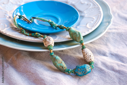 Bohemian beads handmade of polymer clay on beautiful plate. Still life boho chic style.