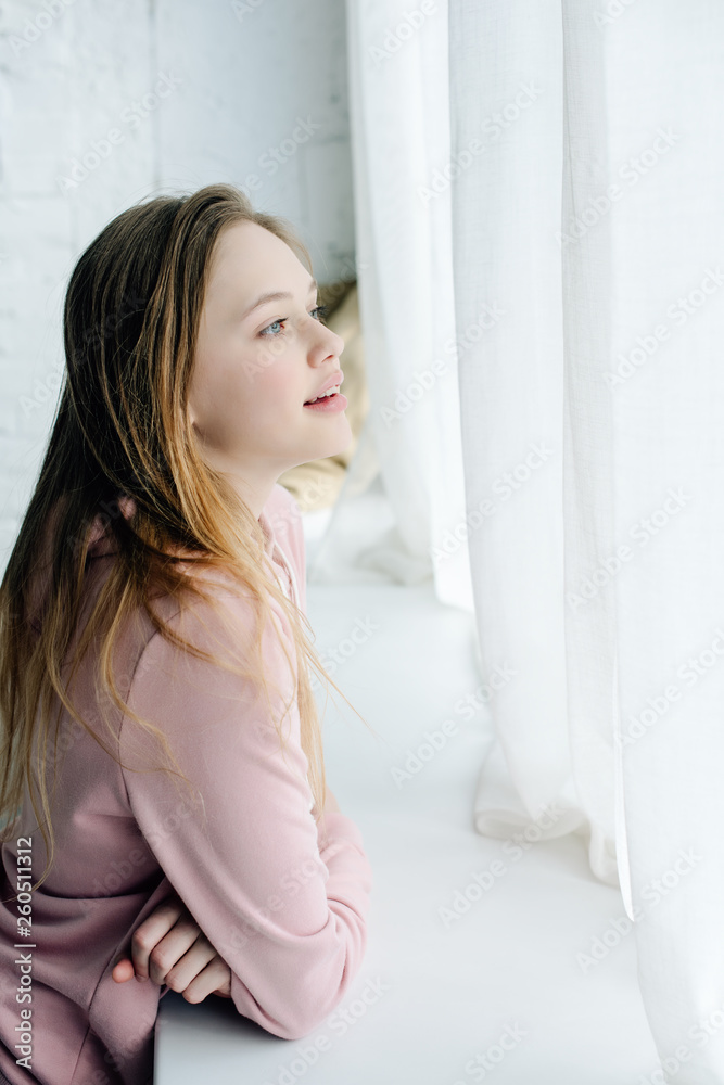 Teenage kid in pink hoodie standing near window sill Teenage kid in pink hoodie standing near window sill