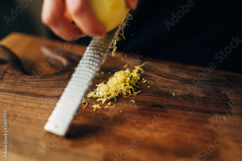 Bilde på lerret Female chef grating lemon zest on a wooden board