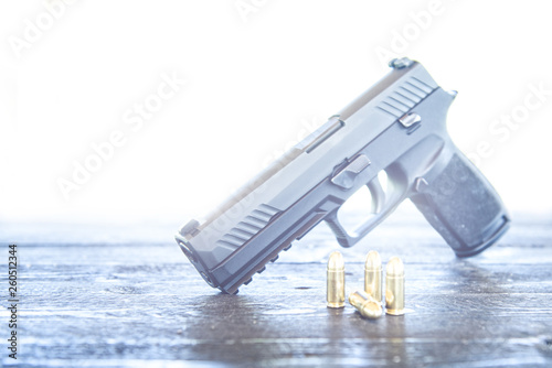 Gun with ammunition on wooden background photo