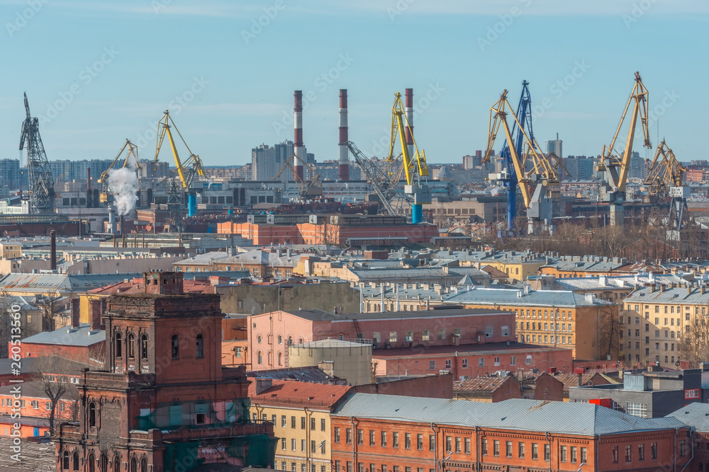 View of the industrial rafon of the city with factories and old industrial buildings, including the port and marine cargo cranes.