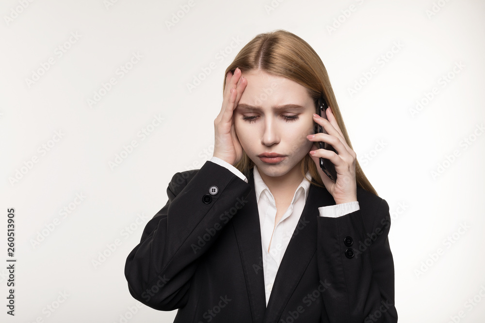 Portrait of a furious european businesswoman talking on mobile phone, holding hand on head Portrait of a furious european businesswoman talking on mobile phone, holding hand on head