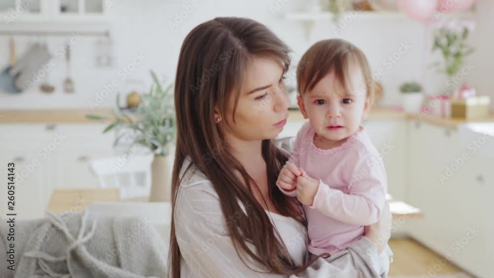 Patient young mother comforting her lovely baby daughter crying in her arms Patient young mother comforting her lovely baby daughter crying in her arms