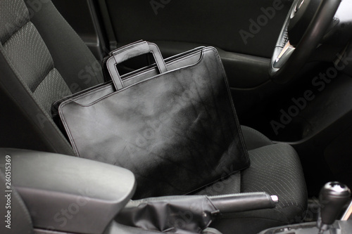 Stylish black business man's leather bag on the rdiver seat in the car with modern interior