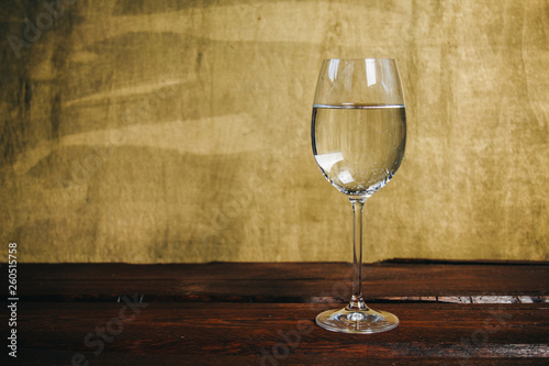 cropped glass of white wine on a rustic wooden brown background. rest, holiday, party. alcoholic drink closeup. copy space