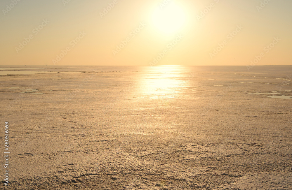 Frozen sea at sunny sunset.