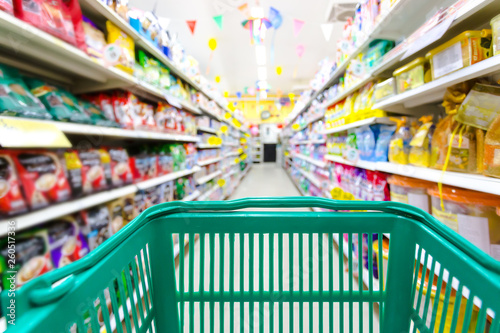 Closeup shopping basket green color with blurred suppermarket background photo