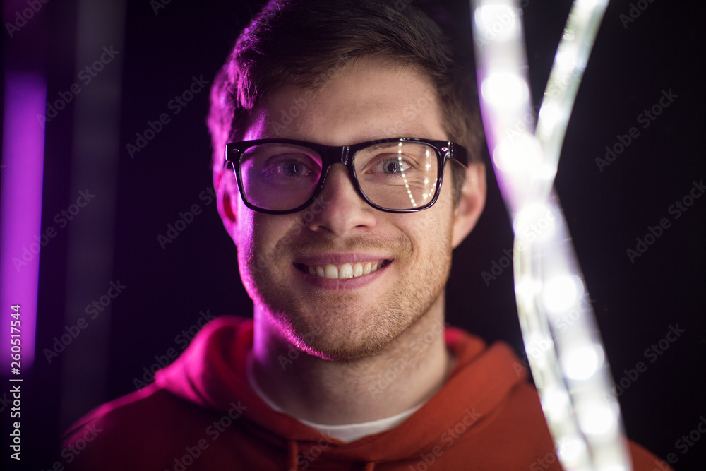 vision, eyewear and people concept - portrait of smiling young man in glasses over ultra violet neon lights in dark room vision, eyewear and people concept - portrait of smiling young man in glasses over ultra violet neon lights in dark room