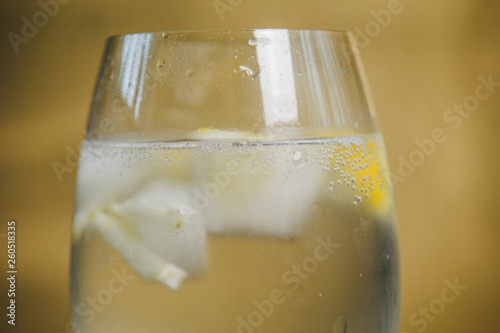 A glass of homemade lemonade with ice and lime on a rustic wooden brown background. rest, holiday, party. crystal glass closeup. copy space