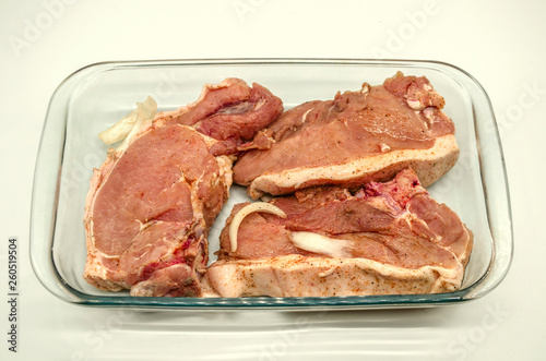 Marinated fresh large pieces of pork, sprinkled with spices for a barbecue in a glassware