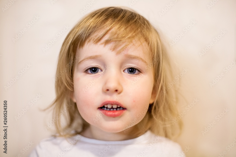 closeup face portrait of cute two years old blonde white girl on wall background closeup face portrait of cute two years old blonde white girl on wall background
