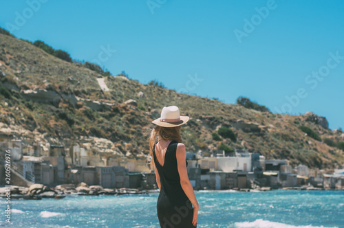 Portrait of girl in black dress staying by back on windy beach