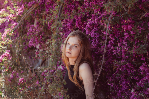 Billede på lærred Portrait of girl among purple bougainvillaea