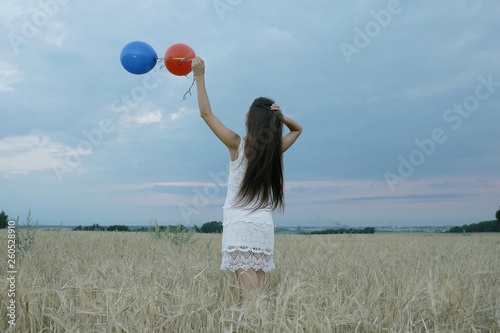 Dream, happiness - young girl in a field with flying balloons