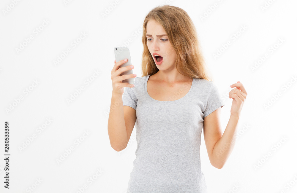 Angry teen woman in grey shirt shouting on smartphone over white background, bad news reading Angry teen woman in grey shirt shouting on smartphone over white background, bad news reading