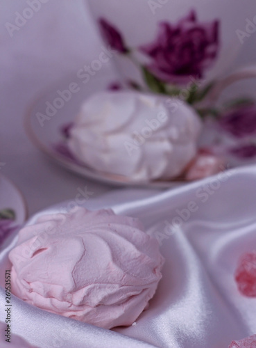 Close-up on a pink zephyr, which lies in front of a cup on the table