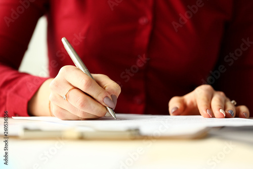Canvas Print Female office worker holding silver pen filling out some application form