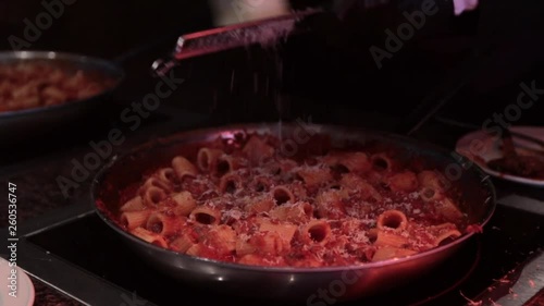 Slow motion grating parmesan on pasta sauté pan