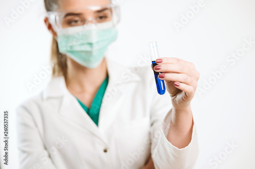 Young nurse holding a test tube, testing liquid.