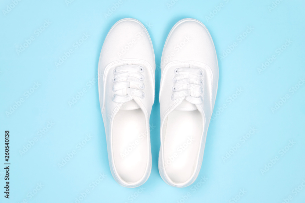 White sneakers on blue background, flat lay..Fashion trend shoe,  concept