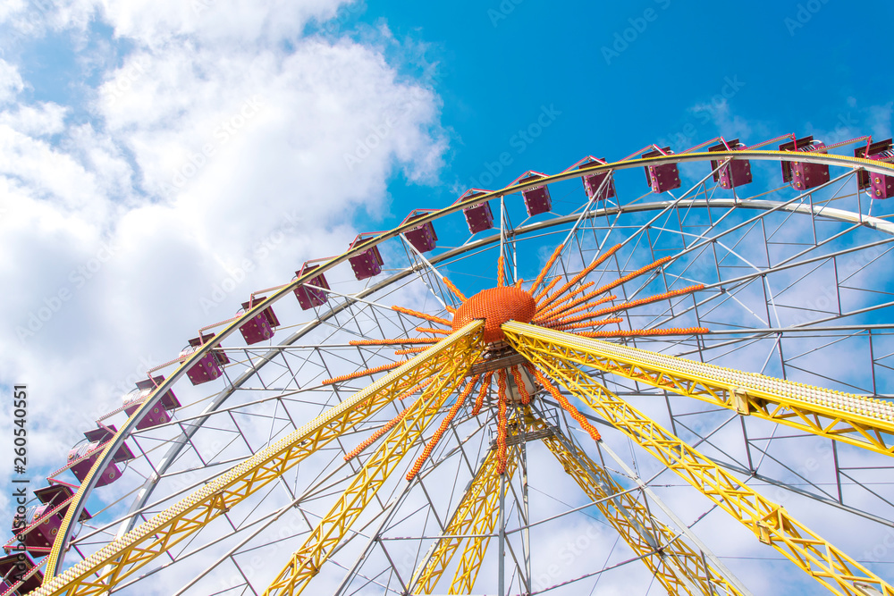 Beautiful ferris wheel on the background of blue sky with clouds
