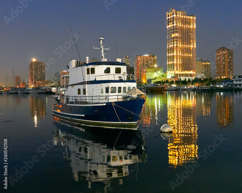 Night scenery of a ship docking at Manila Bay near Manila Yacht Club with illuminated high-rise buildings in the background reflecting in the water photo