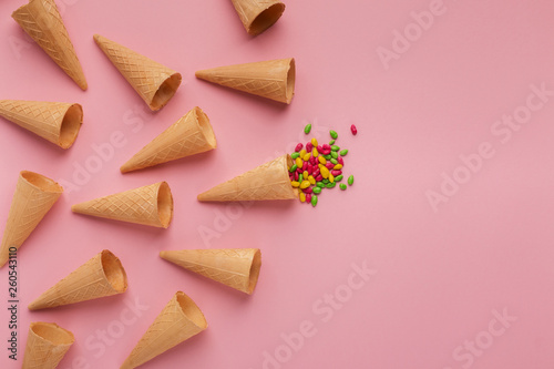 Waffle cones and sprinkles on pink surface