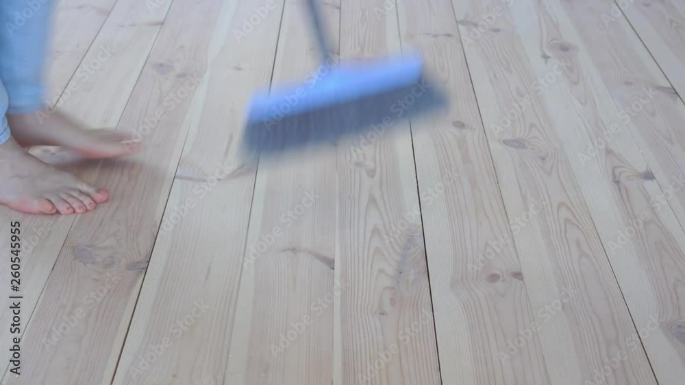 eco-friendly flooring - a woman sweeps a wooden floor eco-friendly flooring - a woman sweeps a wooden floor