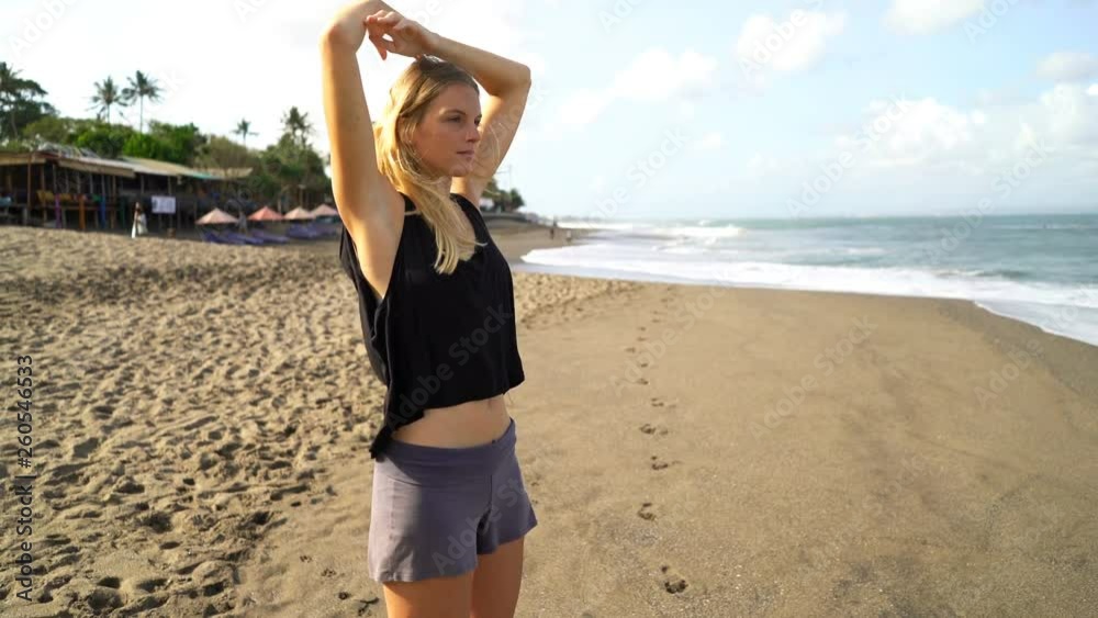 Young, fit woman stretching arms, doing warmup on the beach Young, fit woman stretching arms, doing warmup on the beach
