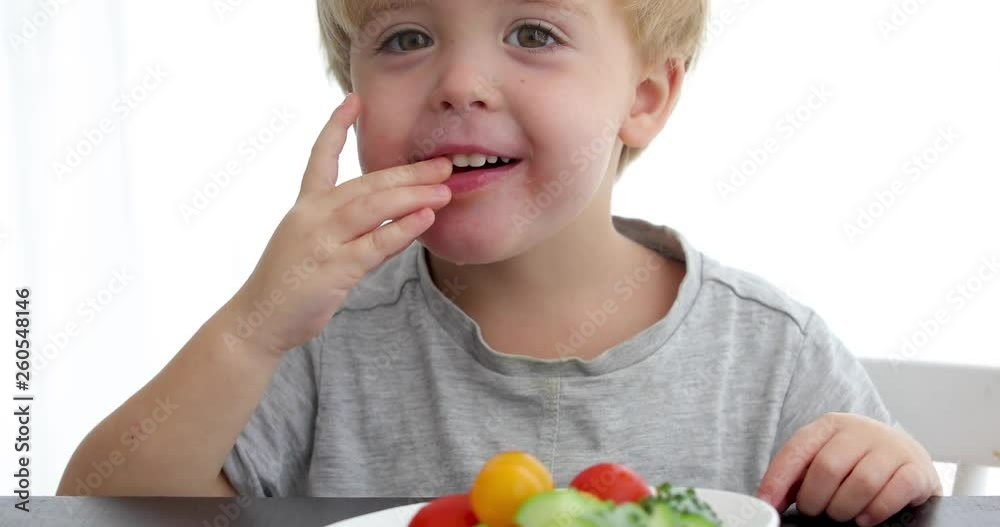 Happy child eating healthy vegetables on white background Happy child eating healthy vegetables on white background