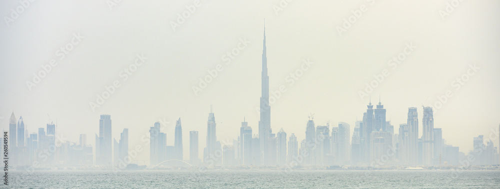 Stunning panoramic view of the Dubai skyline with the magnificent Burj Khalifa and many others towers, skyscrapers and buildings surrounded by a thick morning fog. Dubai, United Arab Emirates.