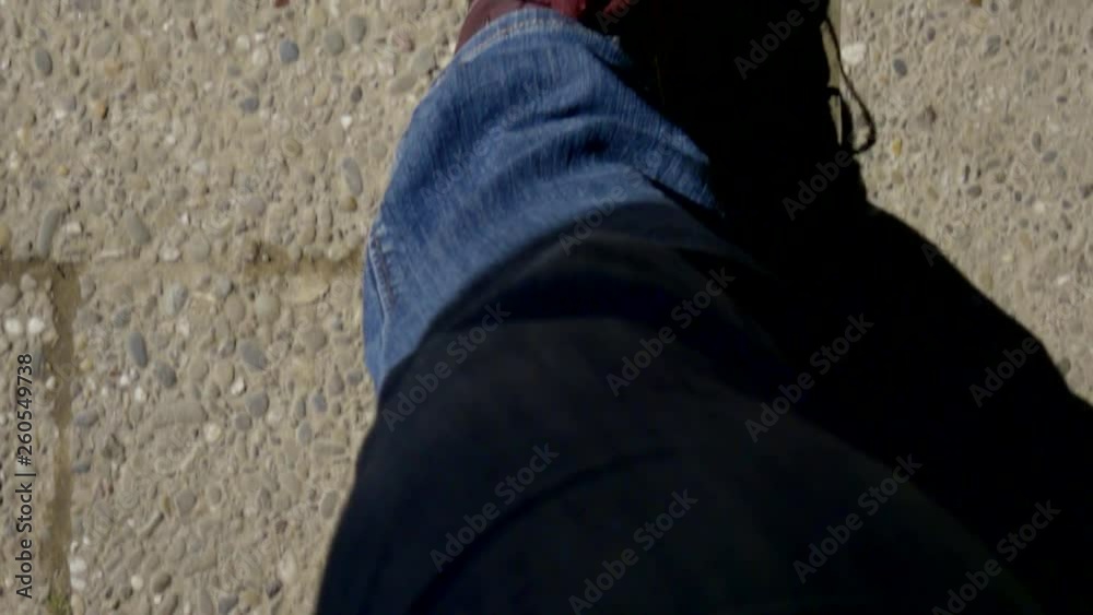 Shot from above of a man in a red sneakers walking on city streets in sunny day. Shot from above of a man in a red sneakers walking on city streets in sunny day.