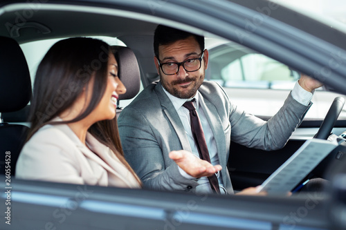 Professional salesperson selling cars at dealership to buyer