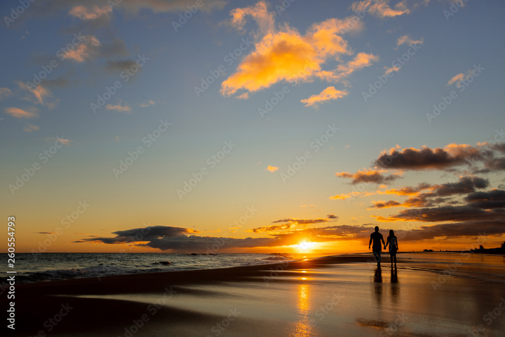 happy couple walking on seashore on a beach vacation or honeymoon trip