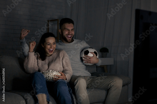 Young couple watching football match on television