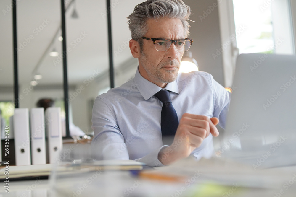 © goodluz - Businessman wearing glasses working in contemporary office