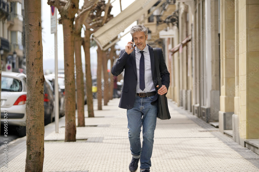 Businessman commuting on foot with cellphone