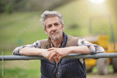 Fotografia Attractive farmer leaning on fence looking at camera