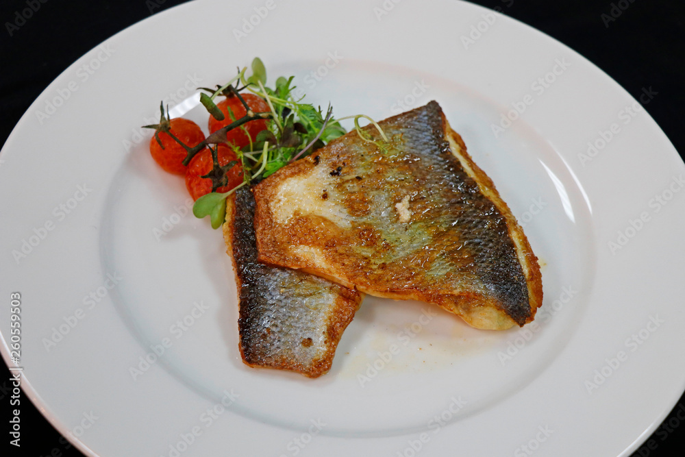 pan fried sea bass in a white plate pan fried sea bass in a white plate