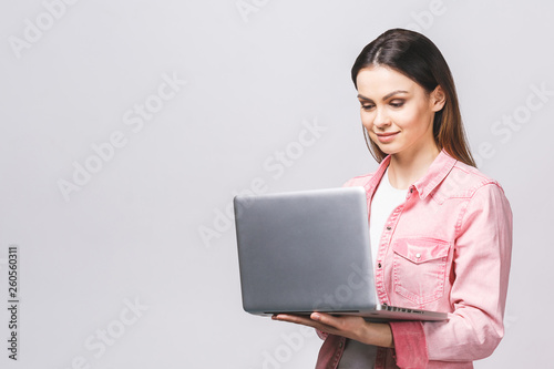 Pretty young businesswoman in casual holding laptop in the office, isolated against whiate background. photo