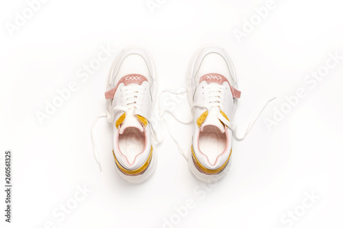 White female sneakers on white background. Fashion blog or magazine concept. Women's shoes, trendy sneakers, fashion, style, lifestyle. Flat lay top view copy space minimal background.