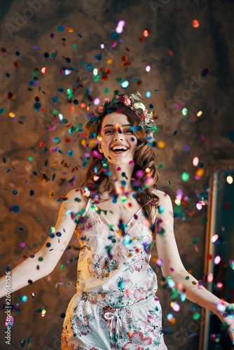 Happy beautiful woman celebrating with confetti falling everywhere on room