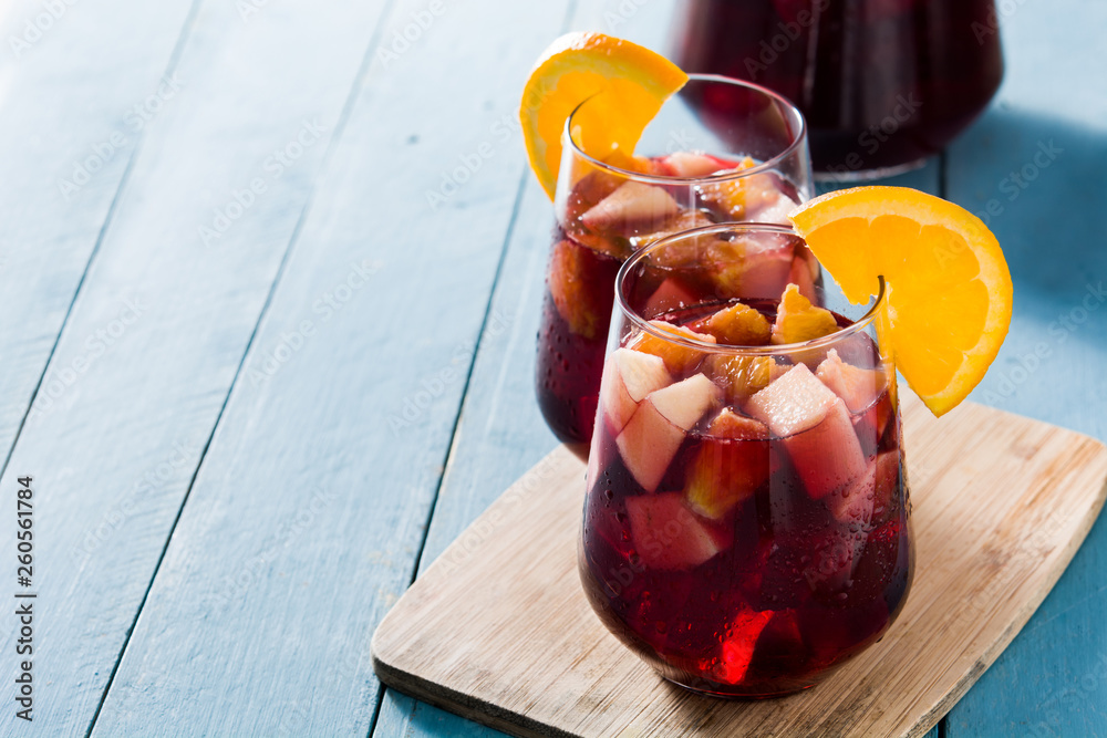 Red wine sangria in glass on blue wooden table. Copyspace - obrazy, fototapety, plakaty 